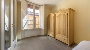 A room with a wooden wardrobe, a window with a view, and a door leading to another room. - UR-NEST d'Azeglio, Elegant one bedroom apartment (Bologna)