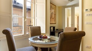 A room with a round glass table, two upholstered chairs, a painting on the wall, and a door leading to another room. - UR-NEST d'Azeglio, Elegant one bedroom apartment (Bologna)