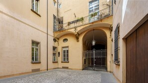 A courtyard with cobblestone flooring, a wooden door, and a metal gate. - UR-NEST d'Azeglio, Elegant one bedroom apartment (Bologna)