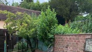 A patio area with two metal tables and chairs, a brick wall, and a small lawn. - 16 century house in beautiful Norman village (Lyons-la-Forêt)