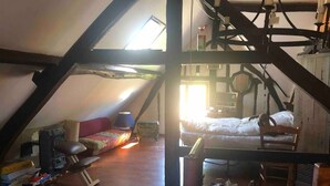 A loft-style room with a sloped ceiling, a bed, a sofa, and a small table. - 16 century house in beautiful Norman village (Lyons-la-Forêt)