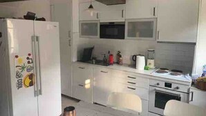 A compact kitchen with white cabinets, a microwave, a stove, and a refrigerator. - 16 century house in beautiful Norman village (Lyons-la-Forêt)