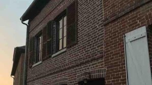 A brick building with multiple windows and doors, some of which are open. - 16 century house in beautiful Norman village (Lyons-la-Forêt)