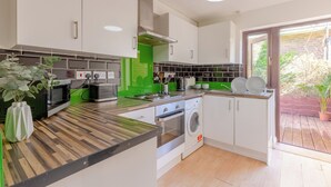 A modern kitchen with white cabinets, a built-in oven, microwave, and washing machine. - Beautifully Presented 2BD House, South East London (London)