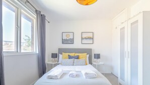 Ein modernes Schlafzimmer mit einem Bett, zwei Nachttischen, einem Kleiderschrank und zwei Wandbildern.