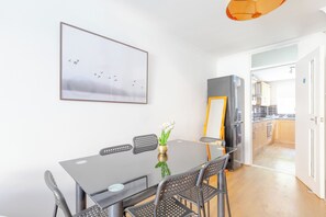 A dining area with a table, chairs, and a framed picture on the wall. - Stylish 4BD Home with Garden Near Kennington (London)