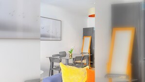 Ein Essbereich mit einem Tisch, Stühlen, einer Blumenvase und einem gerahmten Bild an der Wand.