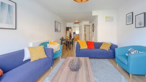 Ein modernes Wohnzimmer mit zwei Sofas, einem Couchtisch und einem Essbereich im Hintergrund.