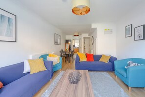 En moderne stue med to sofaer, et sofabord og et spiseområde i baggrunden.
