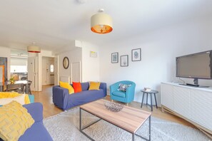 A modern living room with a sofa, armchair, coffee table, and a television.