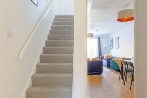 A staircase leading to a living area with a sofa, chairs, and a hanging light fixture. - Stylish 4BD Home with Garden Near Kennington (London)
