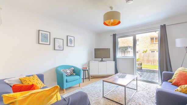 Ein modernes Wohnzimmer mit Sofa, Sesseln, Couchtisch und Kunstwerk an der Wand.