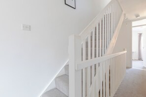 A staircase with white railings and carpeted steps leading to an open area.