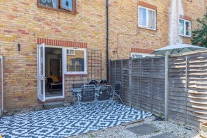 A brick building with a patio area, outdoor seating, and a wooden fence.