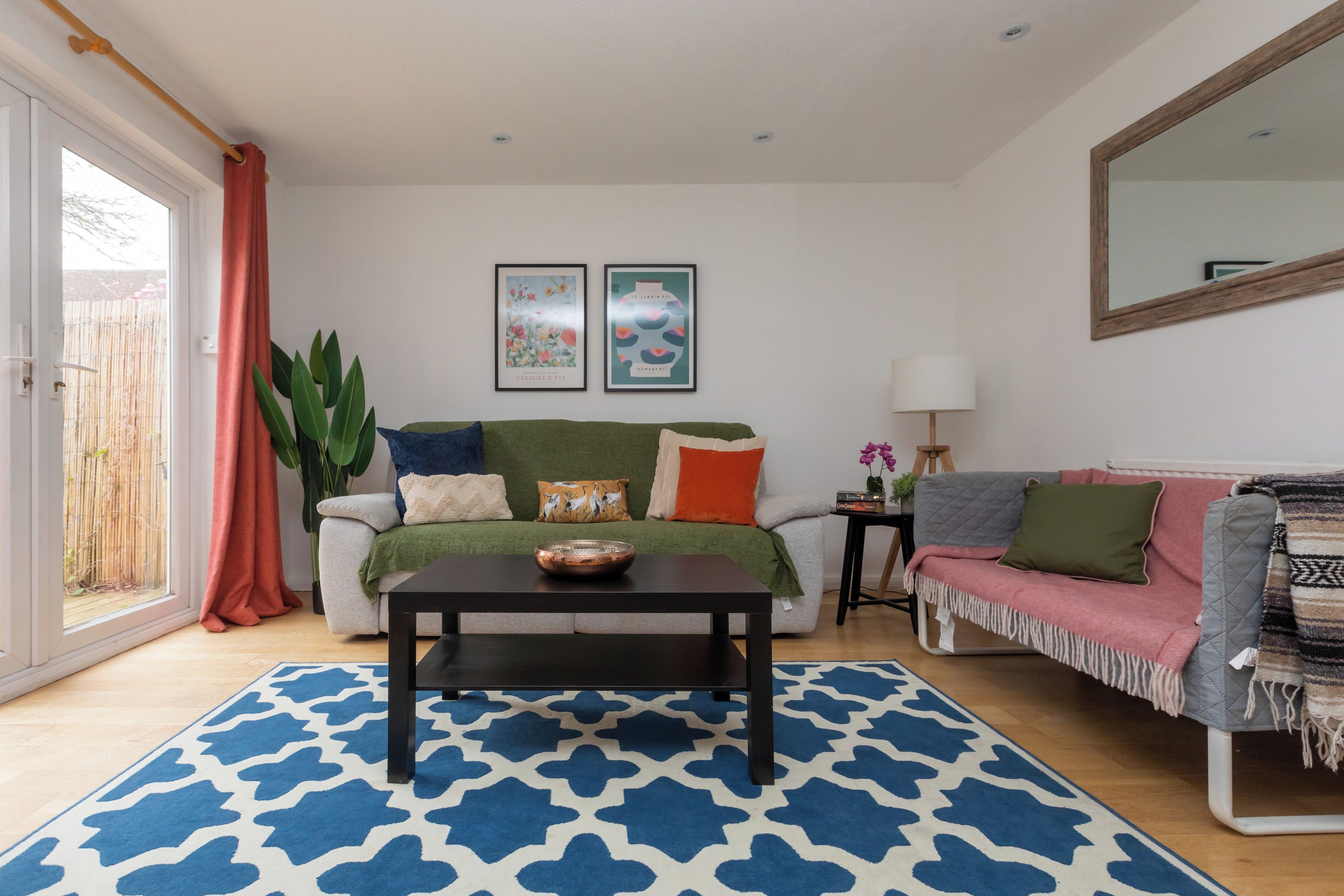 A living room with a sofa, a coffee table, and a side table. There are two framed pictures on the wall.