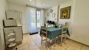 A compact kitchen with a refrigerator, a sink, and a dining area with a table and chairs. - T2 45m2 with garden, Air conditioning, Parking, Quiet, Comfortable, Beach 800m (Saint-Raphaël)