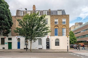 A multi-story building with a traditional architectural style, featuring a mix of brick and stone facades, and a prominent tree in front. - Modern 2BDR City Retreat Angel & Shoreditch Border (London)