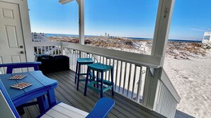Eine überdachte Terrasse mit Blick auf den Strand, ausgestattet mit Tisch und Stühlen.