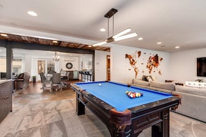Une table de billard dans une pièce au design moderne, avec un coin repas et un espace de détente.