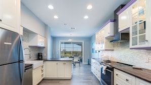 A modern kitchen with stainless steel appliances, white cabinetry, and a wooden countertop. - Beautiful Pool Home with Spa & Games Room in Golf Community Close to Disney (Davenport)