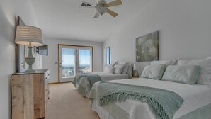 Ein Schlafzimmer mit zwei Betten, einem Deckenventilator, einer Lampe, einem Schminktisch und einem Bild an der Wand.
