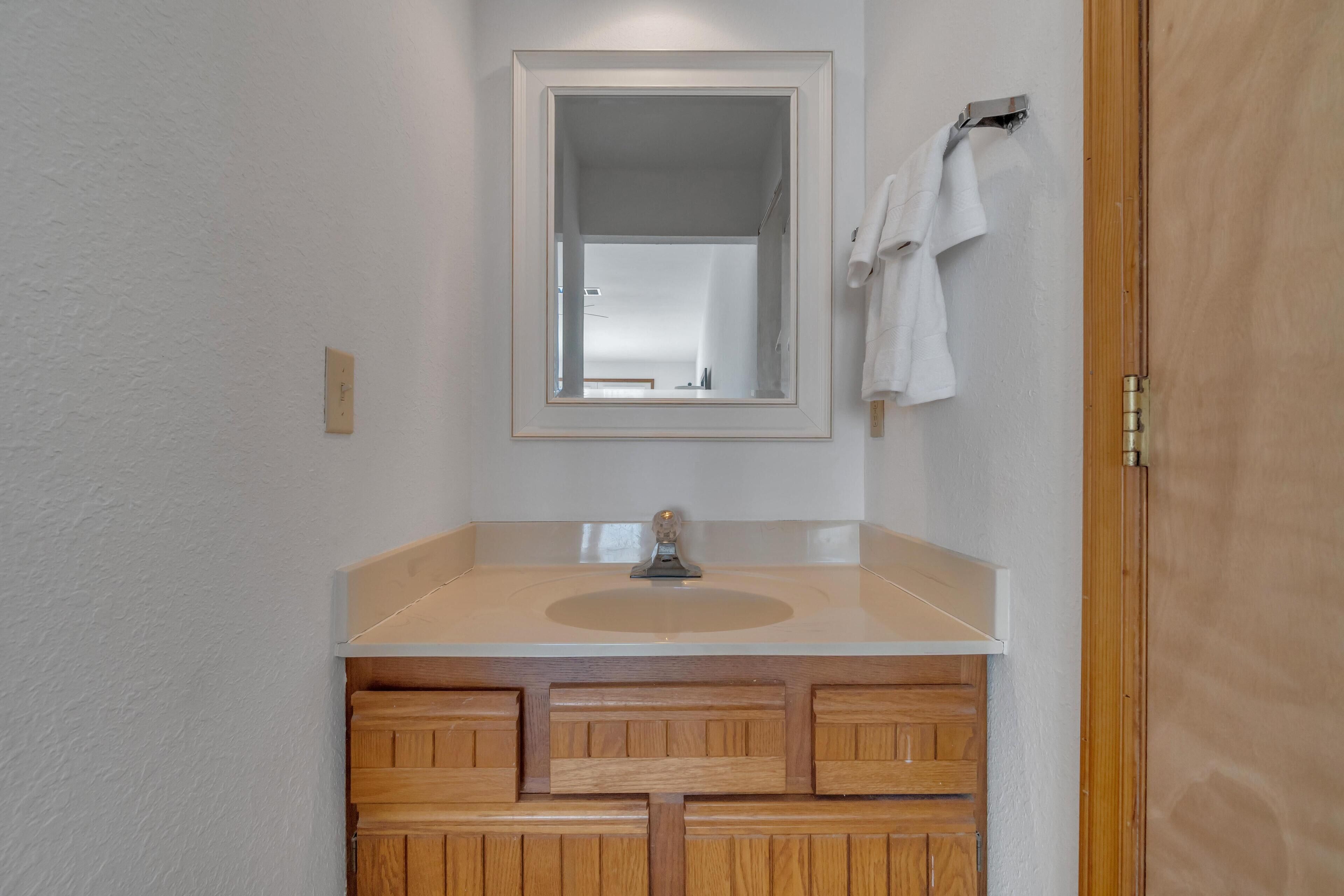 Une salle de bain avec un meuble-lavabo en bois, un miroir et un porte-serviettes.
