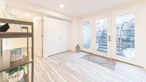 A spacious room with a wooden floor, a white door, and a large window with a view of a staircase.