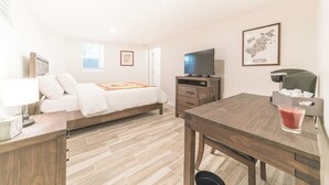 A hotel room with a bed, a TV, a desk, and a framed map on the wall.