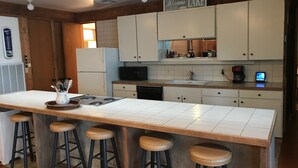 Cucina con isola centrale, sgabelli da bar, forno a microonde, frigorifero e macchina del caffè.