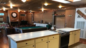 Una cucina con isola centrale, mobili in legno, un fornello e una sveglia appesa al muro.