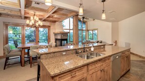 Eine geräumige Küche mit Granit Arbeitsplatten, Holzschränken, einem eingebauten Backofen und einer großen Kochinsel mit Spüle.