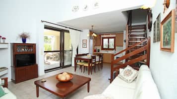 Un vaste espace de vie comprenant une table à manger en bois, un canapé et un escalier menant à un niveau supérieur.