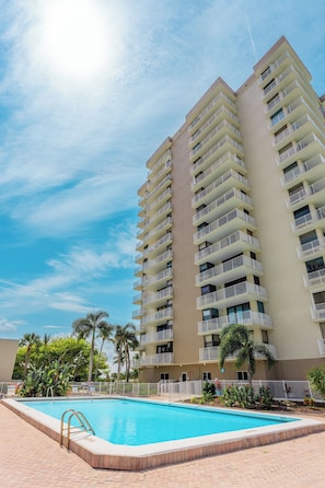 A multi-story hotel with a swimming pool and palm trees.
