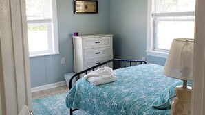 A bedroom with a bed, a nightstand, a dresser, a ceiling fan, and a window. - Shuckers & Beaches!  In Beautiful Mexico Beach, FL (Mexico Beach)