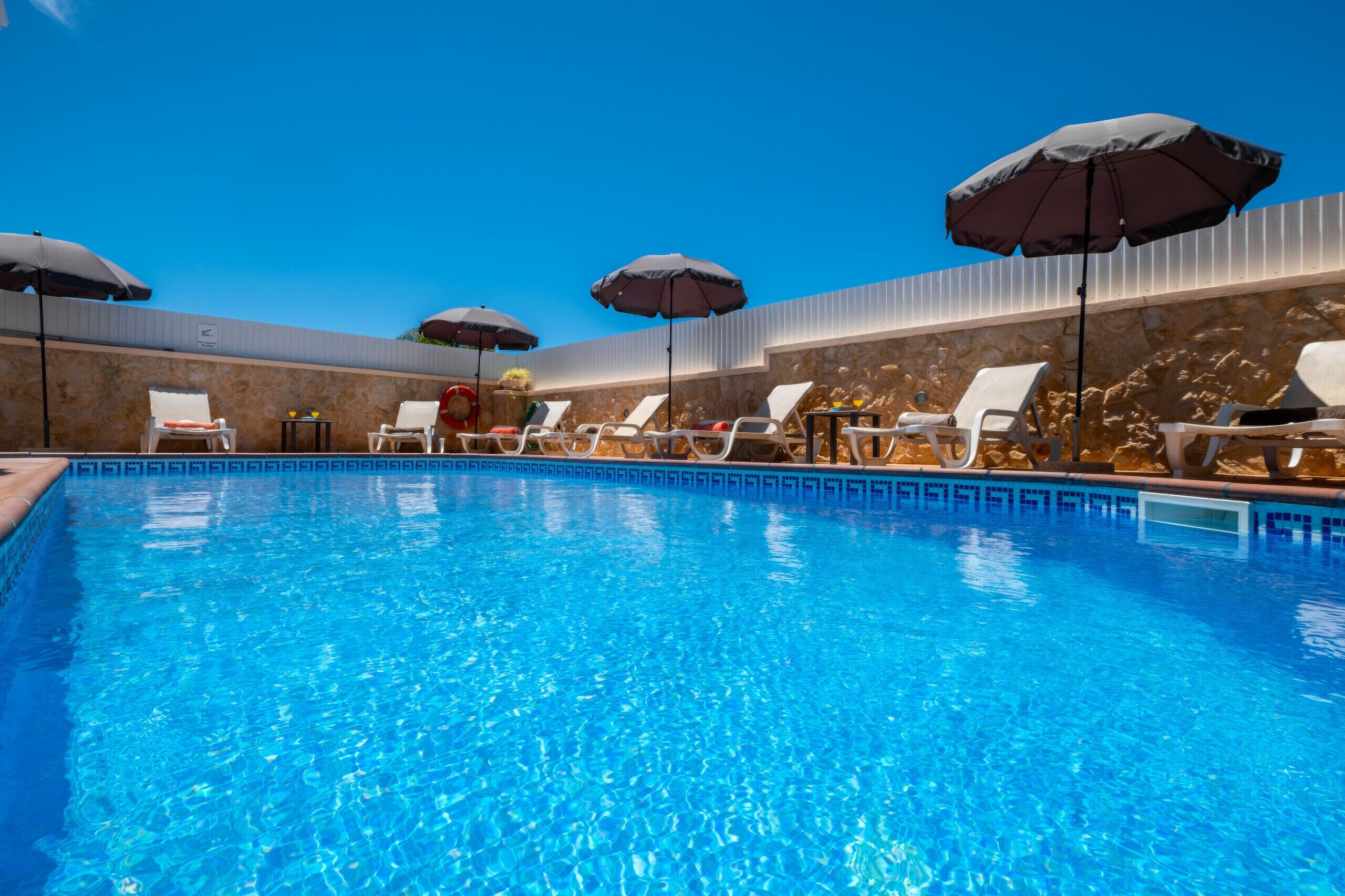 A swimming pool with lounge chairs and umbrellas.