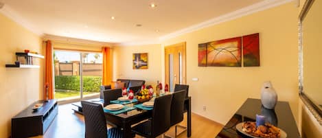 A dining area with a table set for four, a sofa, and a view of the outdoors.