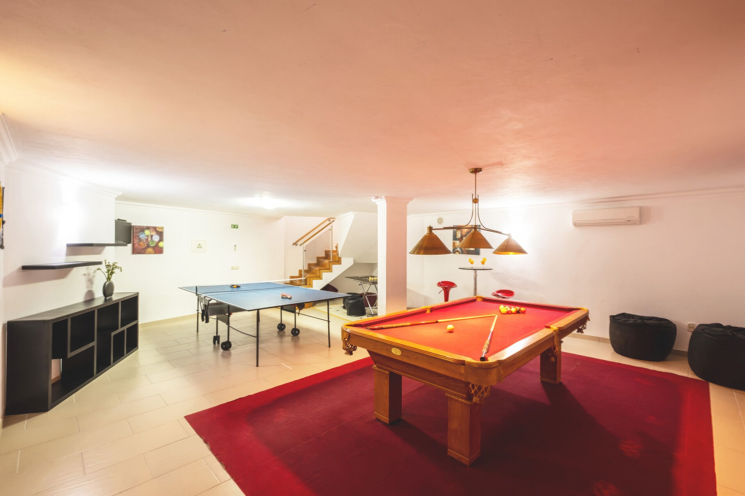A room with a pool table, a ping pong table, and a billiards table.