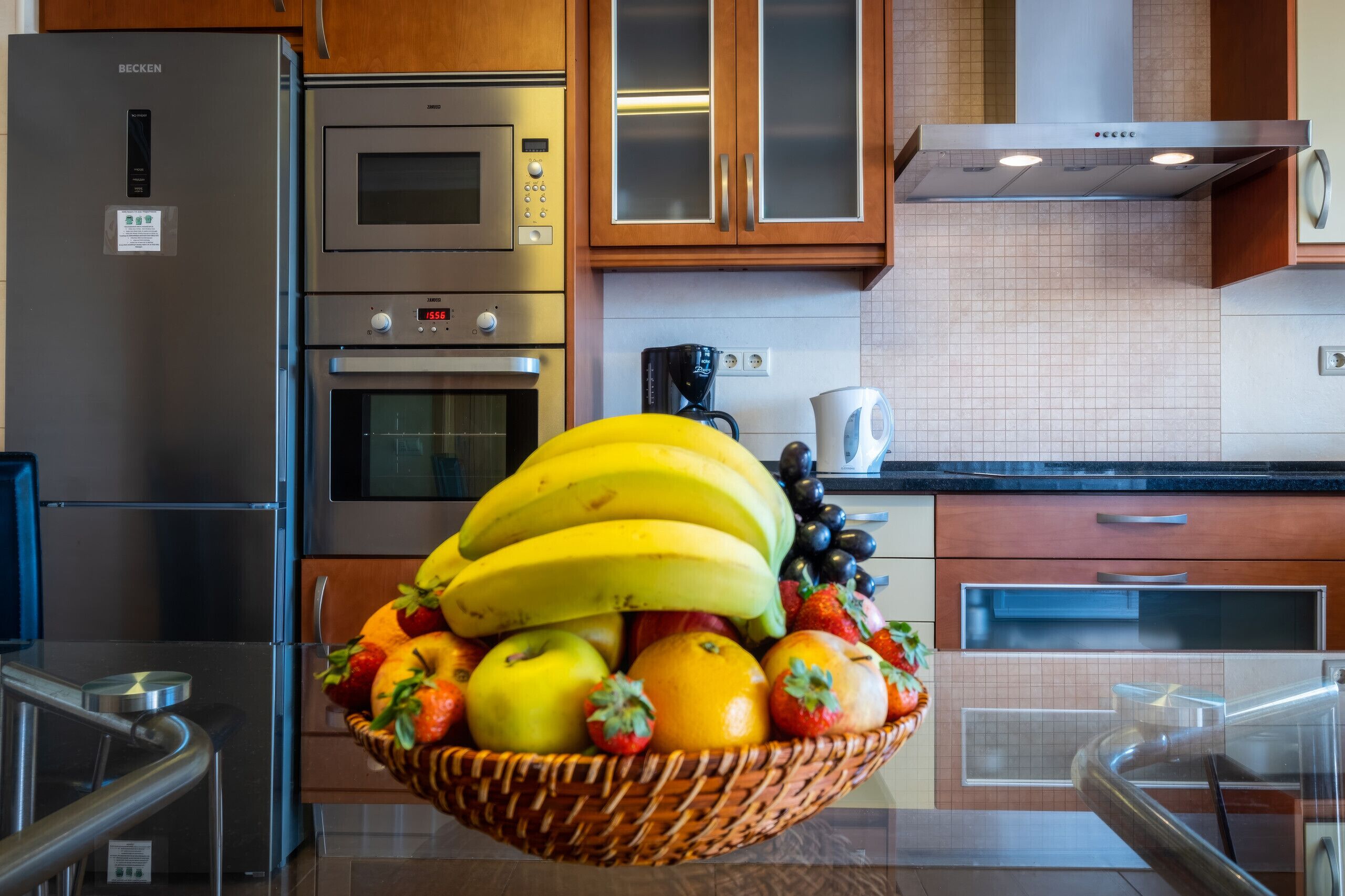 A kitchen with stainless steel appliances, a coffee maker, and a fruit basket on the counter.