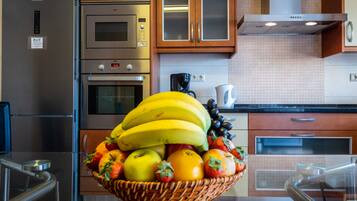 A kitchen with stainless steel appliances, a coffee maker, and a fruit basket on the counter.