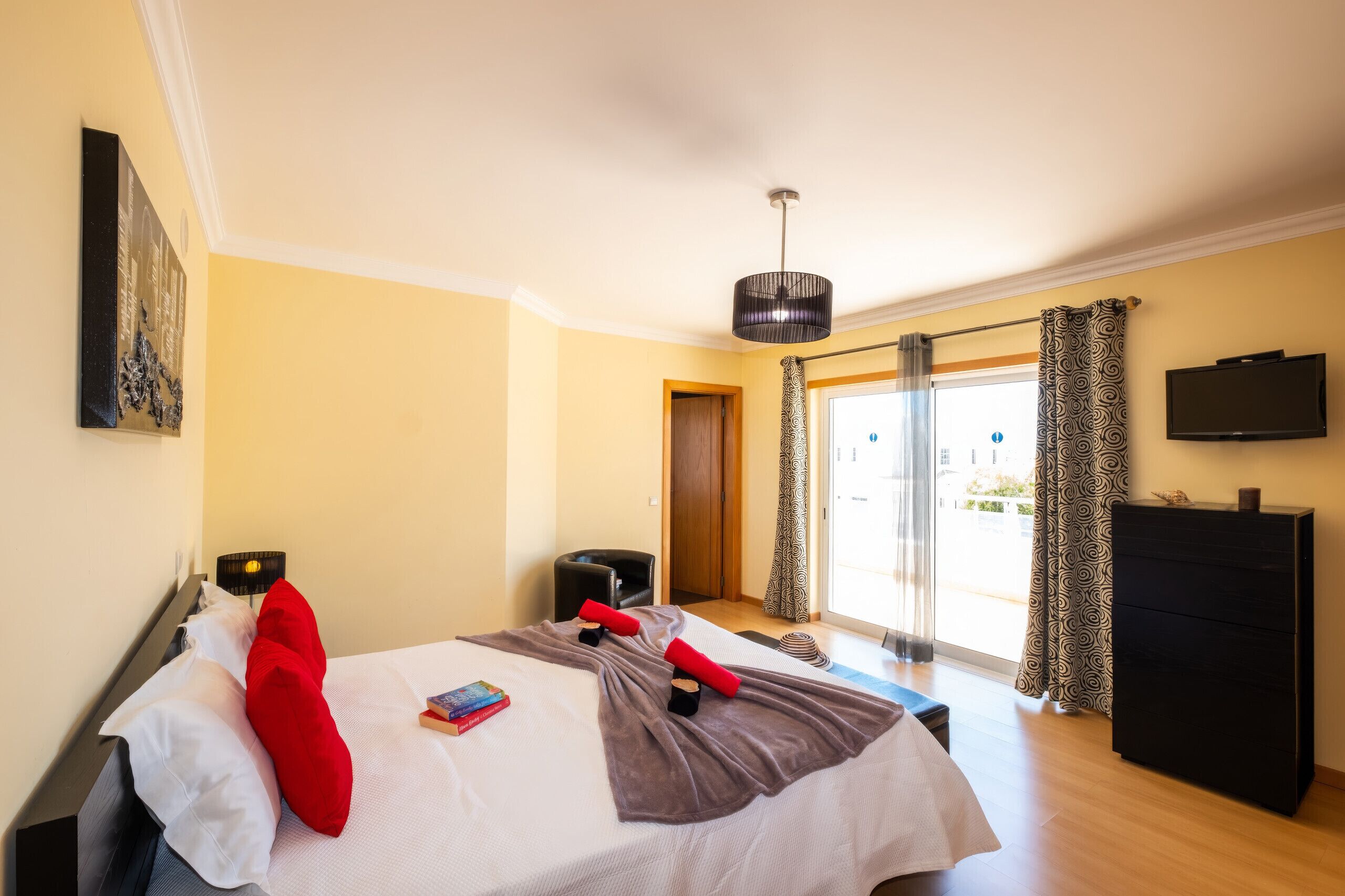 Habitación de hotel con cama, televisor, escritorio y ventana con cortinas.