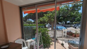 Ein Balkon mit Blick auf einen Parkplatz, ein weißer Stuhl, ein kleiner Tisch und ein Holzschrank.