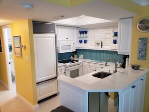 Kitchen features a central island with a sink, microwave, stove, and refrigerator.
