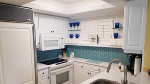 A modern kitchen with white cabinetry, a microwave, a stove, and a sink. - Crescent Arms Luxurious Gulf front Siesta Key Condo 604S (Siesta Key)