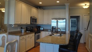 A kitchen with white cabinets, a stainless steel refrigerator, a microwave, and a sink. - Turtle Bay 15 - Riverfront - Dock & Pool (Folly Beach)