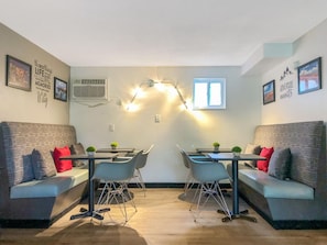 A modern living room with a sofa, two dining tables, and chairs, a window, and wall decorations. - Gatlinburg View Lodge (Gatlinburg)