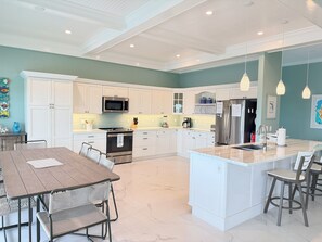A modern kitchen with white cabinetry, a central island, stainless steel appliances, and pendant lighting. - Conch House - Ocean front with dock and pool (Little Torch Key)