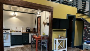 A compact kitchen with a dining area, wooden flooring, and a staircase leading to an upper level. - Barren Lake Waterfront Eclectic Cabin - Dock; 17 miles from Mammoth Cave (Glasgow)