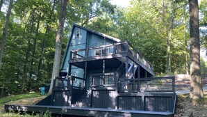 A multi-level wooden cabin with a balcony and stairs, surrounded by trees. - Barren Lake Waterfront Eclectic Cabin - Dock; 17 miles from Mammoth Cave (Glasgow)