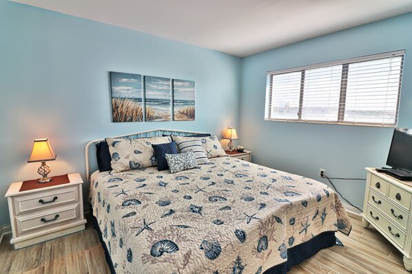 A bedroom with a bed, nightstands, a dresser, and a window.