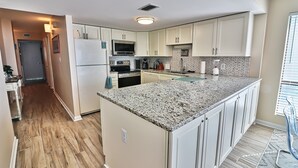 A modern kitchen with white cabinets, granite countertops, and a built-in oven.
